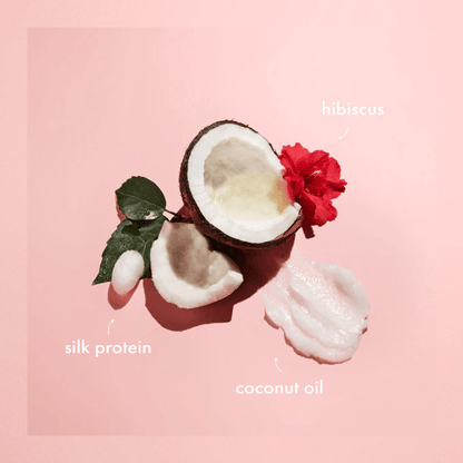 Image of coconut, hibiscus flower, and cream highlighting ingredients like silk protein and coconut oil for SheaMoisture curl and style milk.